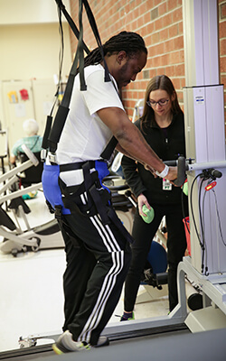 A man is learning to walk again with the assistance of 