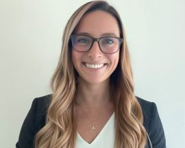 Lauren Vesper smiles while wearing a black blazer and glasses.
