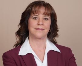 Julie Battard wearing a maroon blazer and a white collared shirt.