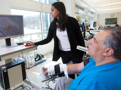Man wearing wrist brace and using a gaming joystick to move items on a monitor.