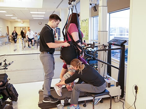 A healthcare professional demonstrating advanced spinal cord rehabilitation technology to a patient.